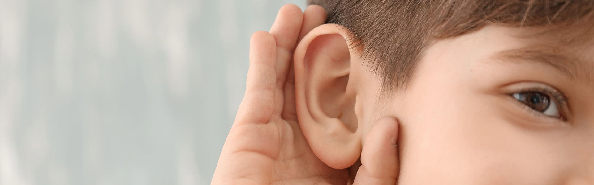 Boy putting hand over his ear. / shutterstock.com