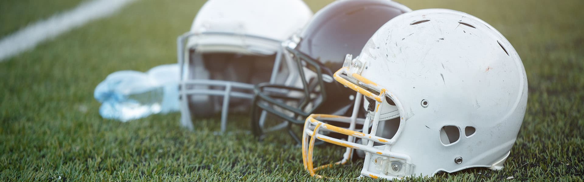 Photo of three football helmets on stadium