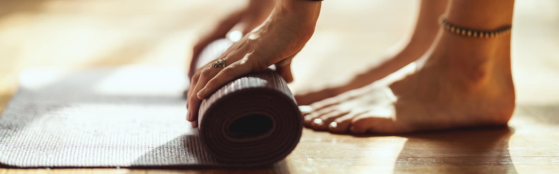 Close up of a womans hands rolling up exercise mat and preparing to doing yoga. / shutterstock.com