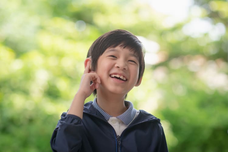 Close-up of young boy being fitted with a hearing aid (ANURAK PONGPATIMET/Shutterstock.com)