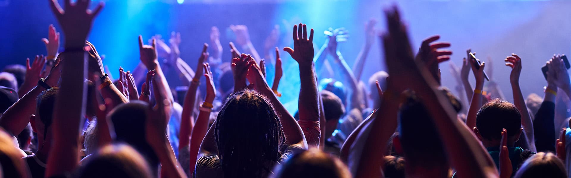 People raise hands in rhythm at outdoor music festival,