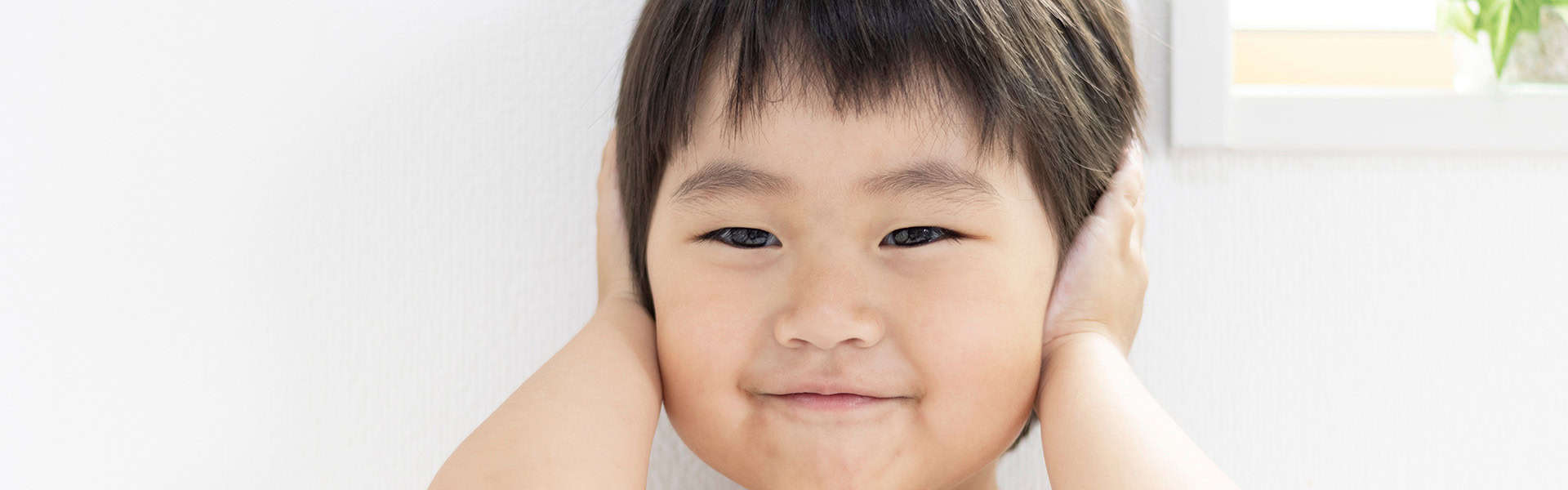 Smiling girl covering both ears / shutterstock.com